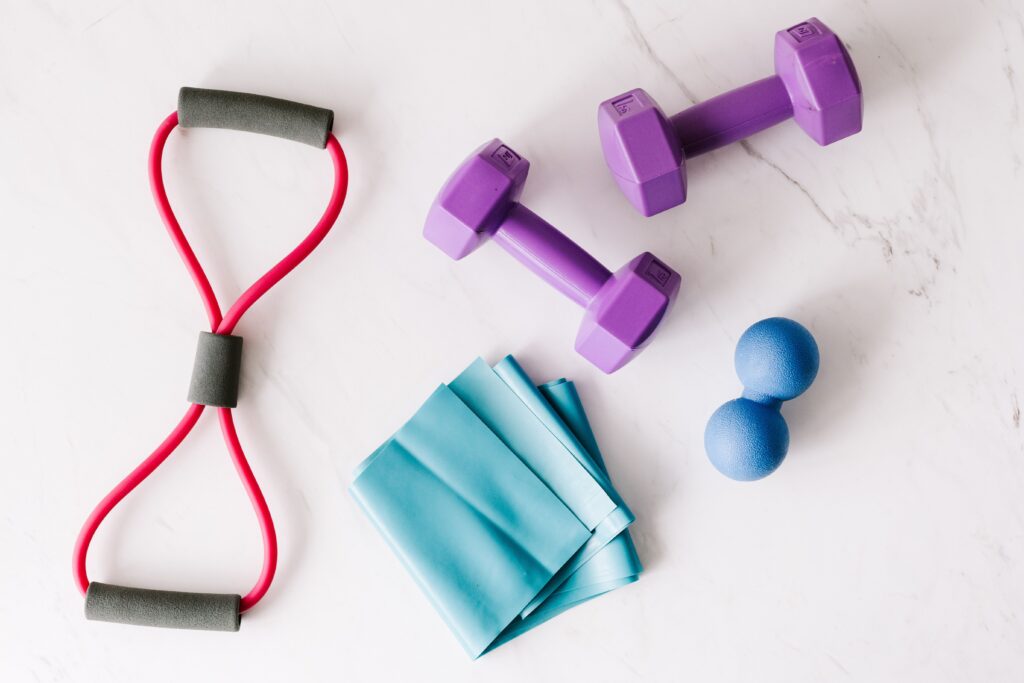 pexels photo 4397831 4397831 Top view of purple metal dumbbells and red tubular expander and blue tape expander and blue massage double ball placed on marble surface