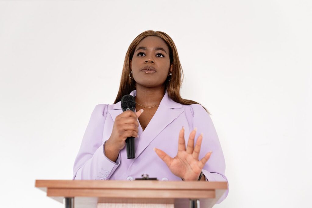 Confident black woman speaking at a podium with a microphone, showcasing leadership and professionalism.